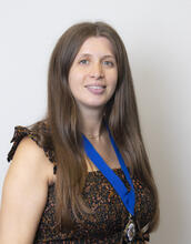 Headshot of Eleanor in a black dress and a medal